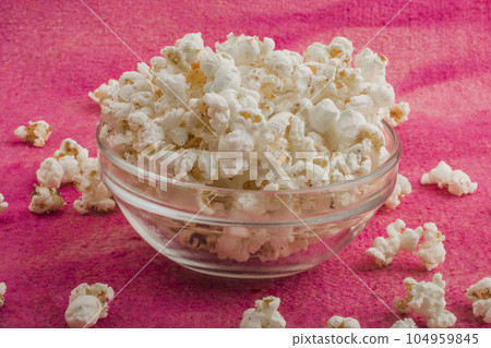 popcorn in a glass plate, on a pink background 104959845