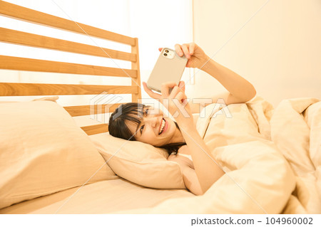 一個在床上使用智能手機的女人 104960002