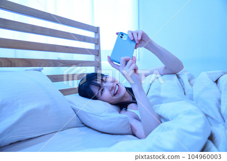 一個在床上使用智能手機的女人 104960003
