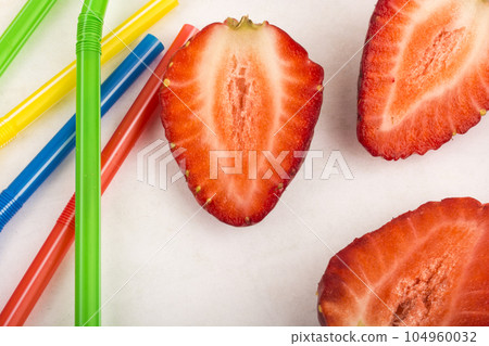 Strawberries and straws scattered on a white background 104960032