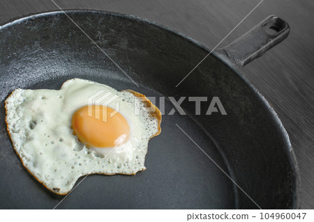 pan with fried eggs on a wooden background 104960047