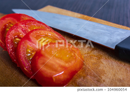 tomato partly sliced with knife and cutting board 104960054