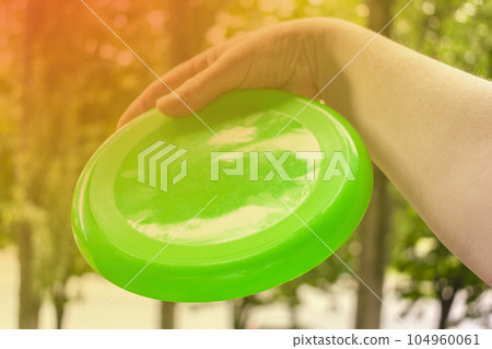 hand throwing a frisbee disc in the park on a summer day hand throwing a frisbee disc in the park on a summer day 104960061