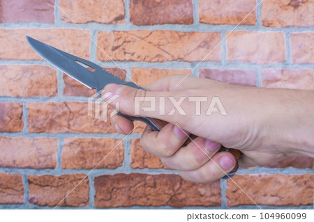 knife in hand, against a brick wall background 104960099