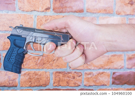 hand of a man with a gun on a brick wall background 104960100
