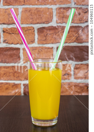 Orange juice Two straws Vitamins Health concept wooden background and brick wall Orange juice Two straws Vitamins Health concept wooden background and brick wall 104960115