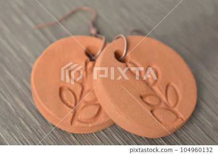 Clay earrings on wooden background Clay earrings on wooden background 104960132