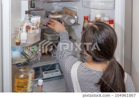 [一位家庭主婦從冰箱裡拿出一個酸梅] 104961867