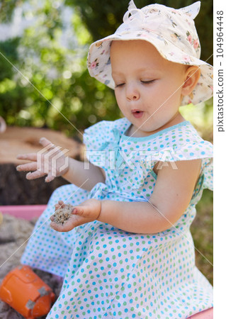 baby girl playing in sand on outdoor playground 104964448