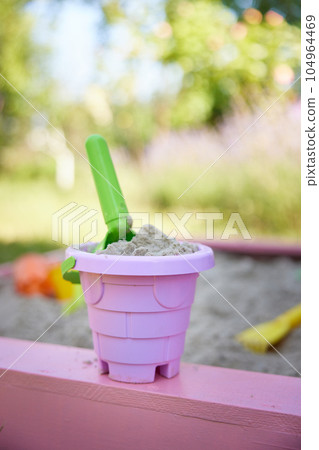pink bucket and green scoop in the sandbox. 104964469