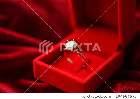Diamond ring in jewelry gift box on red fabric background 104964653