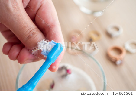 Jeweller hand cleaning and polishing vintage jewelry diamond ring closeup Jeweller hand cleaning and polishing vintage jewelry diamond ring closeup 104965501