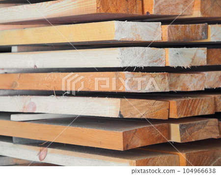 New planed wooden boards stacked in sawmill. Procurement and sale of building material. Dry wood New planed wooden boards stacked in sawmill. Procurement and sale of building material. Dry wood 104966638