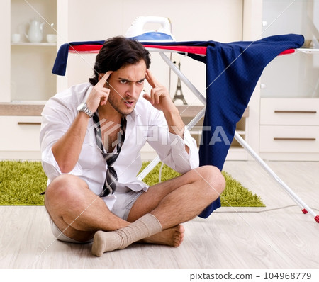 Young man ironing in the bedroom 104968779