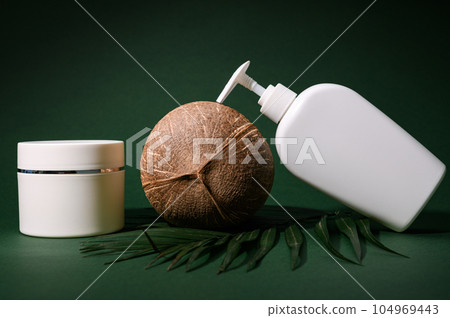 Shower gel with coconut, moisturizing body milk or lotion in a white mockup bottle with a dispenser on green background 104969443