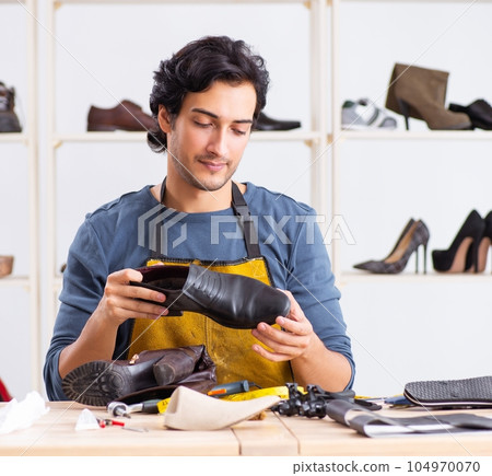 Young man repairing shoes in workshop Young man repairing shoes in workshop 104970070