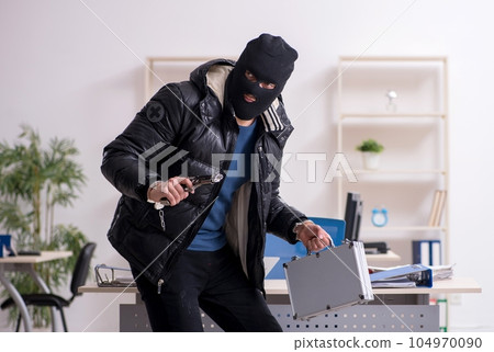 Young male burglar in the office Young male burglar in the office 104970090