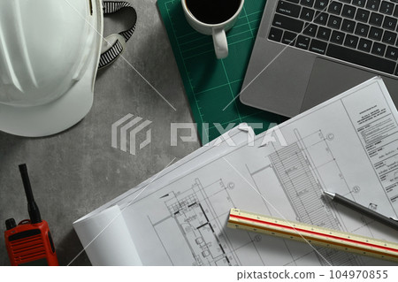 Top view of Architect workspace with laptop, safety helmet. blueprints and walkie talkie on table 104970855