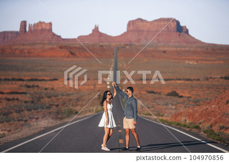 Happy couple on the famous road to Monument Valley in Utah in their trip on Canyon in USA. Scenic highway in Monument Valley Tribal Park in Utah.  104970856