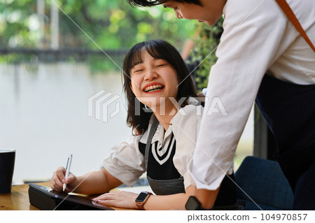 Happy young couple using digital tablet and working together at their coffee shop. Small business management concept Happy young couple using digital tablet and working together at their coffee shop. Small business management concept 104970857