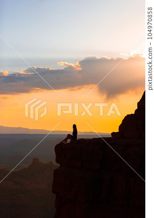 Silhouette of a woman on the trail at Cathedral Rock at sunset in Sedona. The colorful sunset over Sedona's Cathedral Rock landmark. Silhouette of a woman on the trail at Cathedral Rock at sunset in Sedona. The colorful sunset over Sedona's Cathedral Rock landmark. 104970858