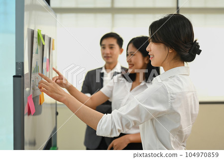 Economist team analyzing financial market, discussing information on whiteboard in meeting room 104970859