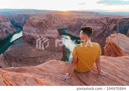 Happy man on the edge of the cliff at Horseshoe Bend Canyon in Page, Arizona. Adventure and tourism concept 104970864
