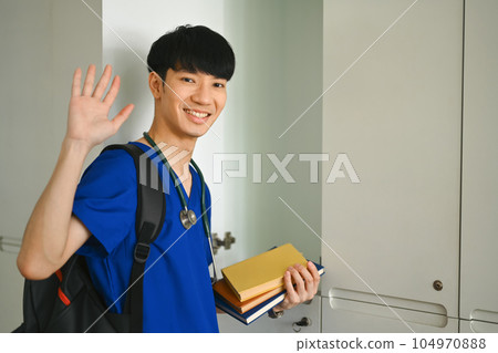 Smiling asian man medical student standing at lockers in campus. Medical internship , education and learning concept Smiling asian man medical student standing at lockers in campus. Medical internship , education and learning concept 104970888