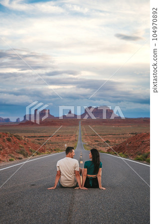 Happy couple on the famous road to Monument Valley in Utah. Amazing view of the Monument valley. 104970892