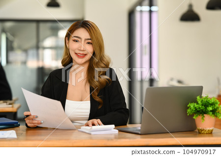 Portrait of asian woman investor using laptop and working on financial document in office 104970917