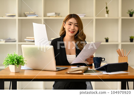 Gorgeous asian female company worker or manager using laptop and working with financial document Gorgeous asian female company worker or manager using laptop and working with financial document 104970920