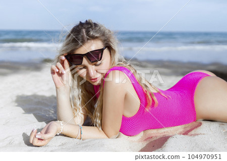 Smiling beautiful woman sunbathing on the beach in sunglasses Smiling beautiful woman sunbathing on the beach in sunglasses 104970951