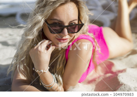 Smiling beautiful woman sunbathing on the beach in sunglasses Smiling beautiful woman sunbathing on the beach in sunglasses 104970983