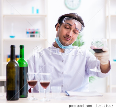 Male chemist examining wine samples at lab 104971007