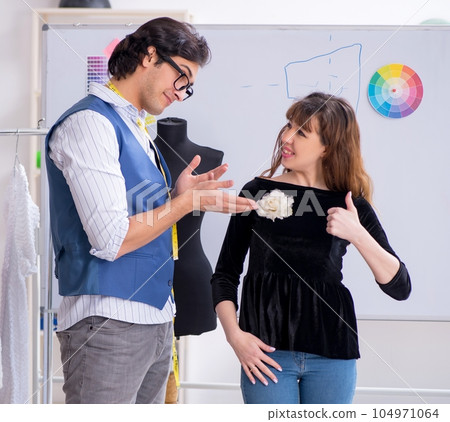 Young male tailor talking to female customer Young male tailor talking to female customer 104971064