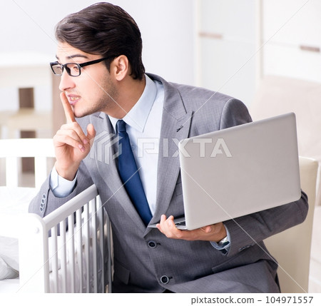 Young businessman trying to work from home caring after newborn 104971557
