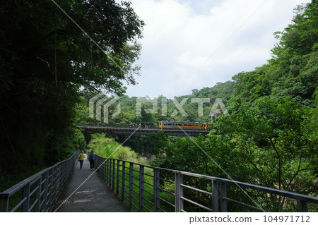 The Guan Waterfall Suspension Bridge seen from the Shifen Waterfall Trail in Taiwan and the Pingxi Line running parallel to it 104971712