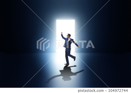 Businessman entering backlit door in escape concept Businessman entering backlit door in escape concept 104972744