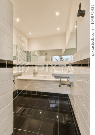 a modern bathroom with black and white tile flooring in the shower area, there is a large mirror on the wall a modern bathroom with black and white tile flooring in the shower area, there is a large mirror on the wall 104973483