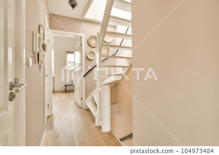 a hallway in a house with white walls and wood flooring, there is a staircase leading up to the second floor a hallway in a house with white walls and wood flooring, there is a staircase leading up to the second floor 104973484