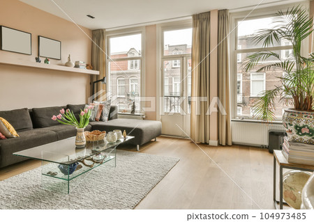 a living room with couches, coffee table and plants in vases on the floor next to the window a living room with couches, coffee table and plants in vases on the floor next to the window 104973485