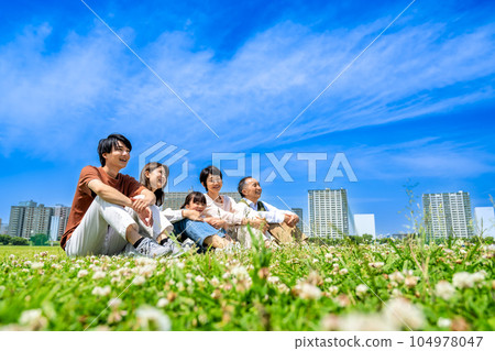 Three generations of close family members relaxing in the park Three generations of close family members relaxing in the park 104978047