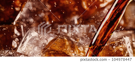 Pouring of Cola and Ice. Cola soda and ice splashing fizzing or floating up to top of surface. Close up of ice in cola water. Texture of carbonate drink with bubbles in glass. Cold drink background Pouring of Cola and Ice. Cola soda and ice splashing fizzing or floating up to top of surface. Close up of ice in cola water. Texture of carbonate drink with bubbles in glass. Cold drink background 104978447