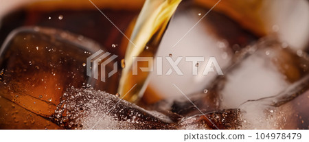 Pouring of Cola and Ice. Cola soda and ice splashing fizzing or floating up to top of surface. Close up of ice in cola water. Texture of carbonate drink with bubbles in glass. Cold drink background Pouring of Cola and Ice. Cola soda and ice splashing fizzing or floating up to top of surface. Close up of ice in cola water. Texture of carbonate drink with bubbles in glass. Cold drink background 104978479