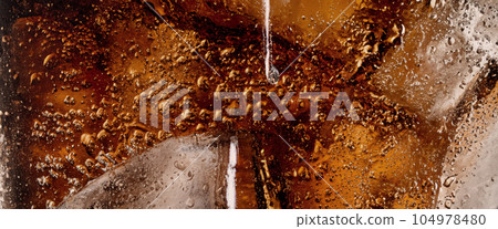 Pouring of Cola and Ice. Cola soda and ice splashing fizzing or floating up to top of surface. Close up of ice in cola water. Texture of carbonate drink with bubbles in glass. Cold drink background Pouring of Cola and Ice. Cola soda and ice splashing fizzing or floating up to top of surface. Close up of ice in cola water. Texture of carbonate drink with bubbles in glass. Cold drink background 104978480