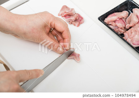 [Housewife preparing yakitori pork tongue with a knife] 104978494