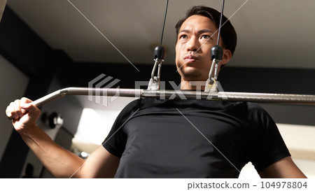 Young man training on lat pull machine 104978804