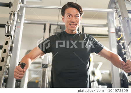 A man working out on a cable machine 104978809