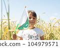 Girl waving flag of Pakistan outdoors over blue cloudy sky and golden wheat. 104979571