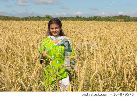 Girl waving flag of Pakistan outdoors over blue cloudy sky and golden wheat. 104979576